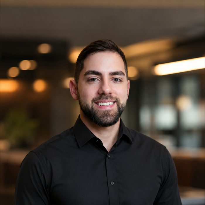 Lucas Anjos, desenvolvedor de software, sorrindo, de camisa preta